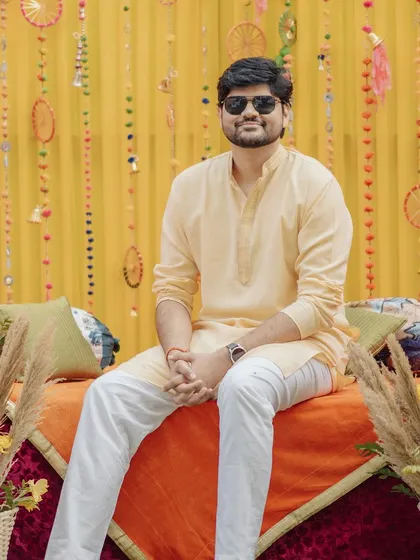A relaxed portrait of the groom before the haldi madness began. The colorful decor in the background sets the festive mood.