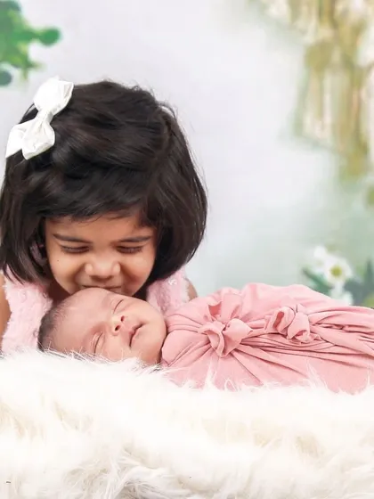 The bond between siblings is a beautiful thing to witness. Here, an older sister gives her newborn sibling a gentle kiss, a heartwarming moment we captured during a family session.
