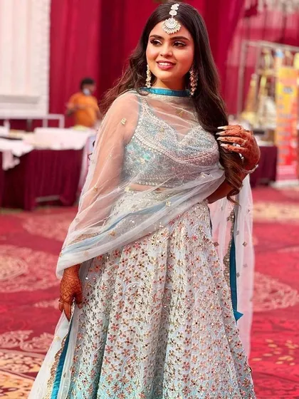 A smiling client looking lovely in her pastel blue rental lehenga. The sheer dupatta and illusion neckline on the blouse add a touch of modern elegance.