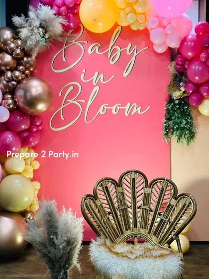 A close-up of the "Baby in Bloom" backdrop, focusing on the elegant script and the stylish peacock chair, perfect for the guest of honor.