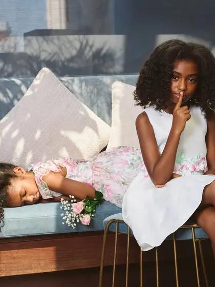 A storytelling moment from a kids' campaign. The dappled sunlight and the playful "shush" gesture create a sweet, narrative-driven image that feels both candid and beautifully composed.