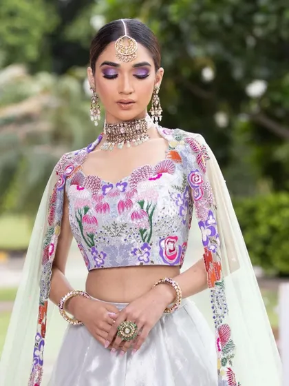 A dreamy mehendi look with a floral embroidered lehenga. The makeup features a soft purple smokey eye, adding a touch of romance and whimsy to the look.