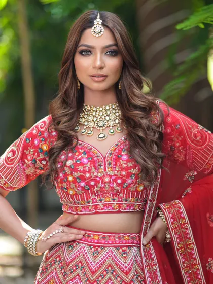 A powerful bridal pose in a multi-colored embroidered red lehenga. The look is completed with a broad Kundan necklace and a simple maang tikka.