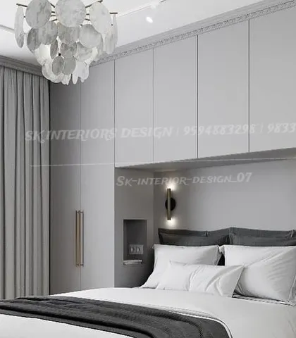 An elegant, monochromatic bedroom with light grey wardrobes that seamlessly blend into the wall. The statement chandelier and minimalist wall sconces add a touch of sophistication.