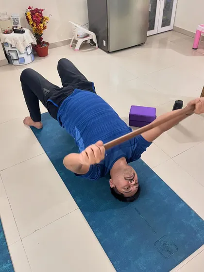 A client uses a stick for a chest and shoulder stretch while lying on his back. This simple technique is highly effective for improving posture and relieving upper body tension.