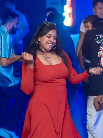 A guest dancing with a big smile, surrounded by friends. The blue and red lights create a classic party atmosphere.