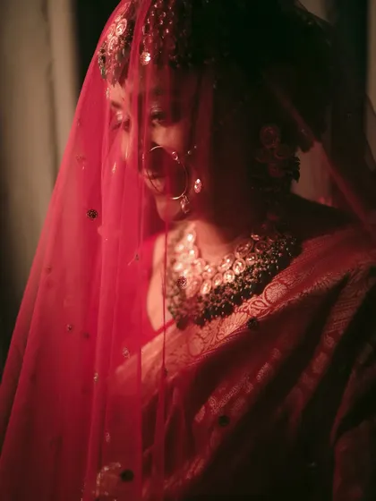A shy, happy smile from the bride, captured through her red veil.