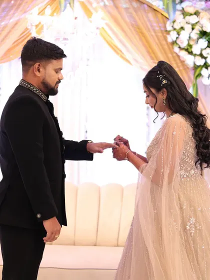 A candid shot of the ring ceremony. Her hairstyle, a beautiful half-updo with long curls, perfectly complements her elegant, flowing gown.