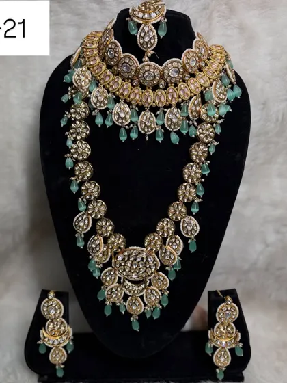 This modern layered set, code B-21, is a favorite among brides. It combines a statement choker with a matching long haar, featuring beautiful mint green beads for a fresh and contemporary look.