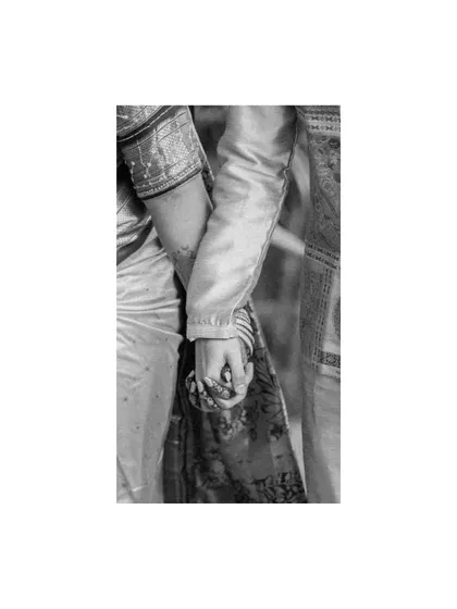 A close-up, black and white detail shot of the couple holding hands, focusing on their intertwined fingers. This simple yet powerful image symbolizes their bond and commitment.