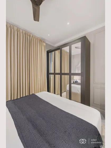 This view of the bedroom highlights the striking black wardrobe with mirrored fronts. The reflection adds depth and light to the space, demonstrating a clever blend of function and modern luxury.
