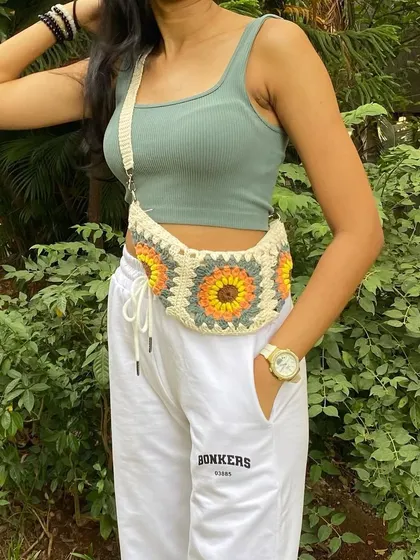 A closer look at the details on our cream granny square fanny pack. Each square is carefully crocheted and stitched together to create a seamless and durable design.