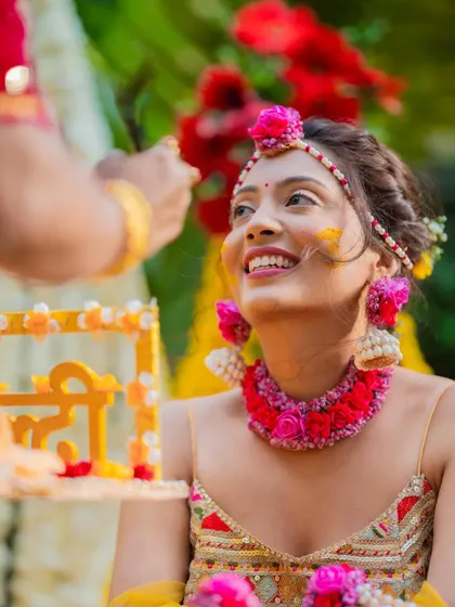 A candid shot of the bride during her Haldi ceremony, her face lit up with a smile as a guest applies turmeric.