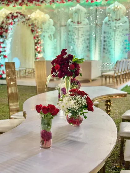 A close-up of the floral arrangements on a curved, marble-top table, featuring deep red and white flowers.