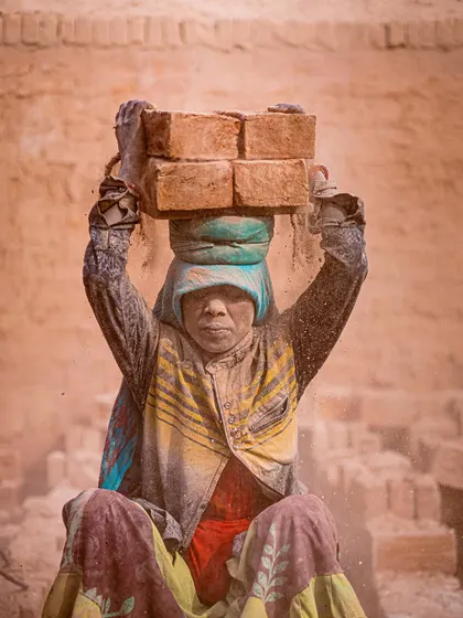 A portrait of a woman worker covered in brick dust. Despite the harsh conditions, her direct gaze conveys a sense of strength and endurance.