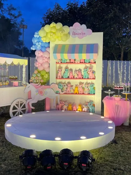 A delightful unicorn-themed party setup, featuring a candy cart-style display with rows of adorable unicorn toys as party favors. The pastel colors and soft lighting create a gentle, magical ambiance.