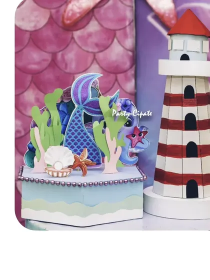 Custom props for a mermaid party, including a miniature lighthouse and a treasure box with a mermaid tail. These details add so much charm.
