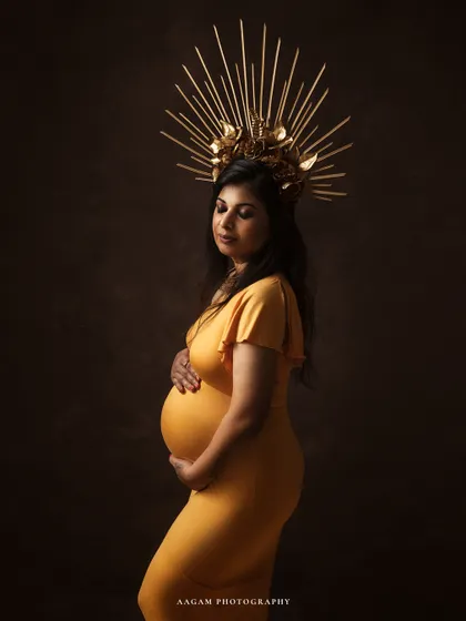 Motherhood is a royal affair. This portrait, with its golden gown and majestic crown, celebrates the queen that every mother-to-be is. It's a statement of strength, grace, and the miracle of creation.