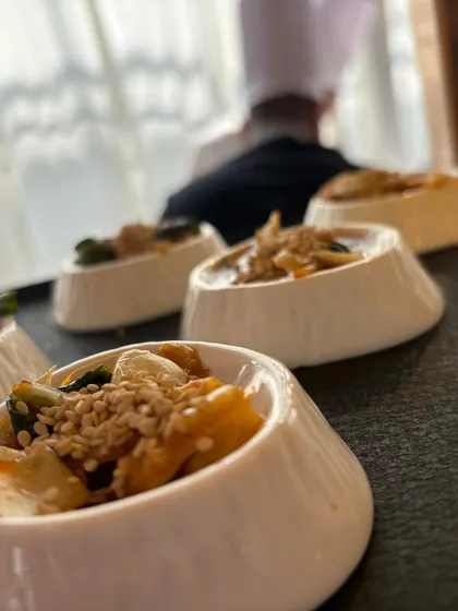 A row of our signature salads ready to be served. The out-of-focus chef in the background gives a sense of the bustling, professional kitchen environment.