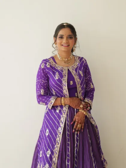 A wedding guest looking pretty in a purple bandhani outfit. The makeup is kept fresh and simple with a pop of color on the eyes.