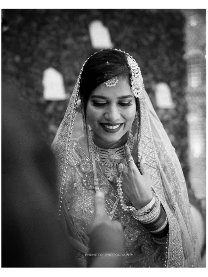 A beautiful black and white portrait of the bride, capturing her joyful expression and intricate jewelry.