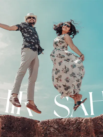 A fun and energetic jump shot from a pre-wedding shoot in Goa, capturing the couple's playful spirit against a bright blue sky.