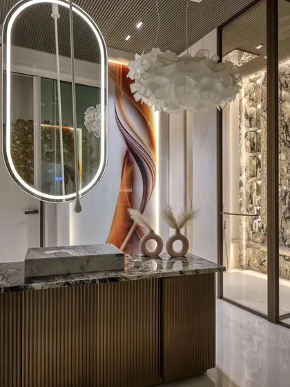 This luxurious bathroom design is a visual delight. The space features a floating vanity with fluted details, a dramatic backlit art panel, and a stunning marble feature wall, blending color, light, and sophistication to create a spa-like experience at home.