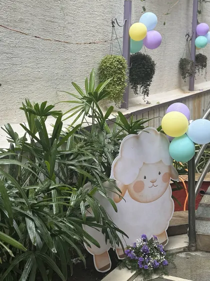 A sweet lamb cutout, holding a bunch of pastel balloons, is nestled among the plants, adding another layer of charm to the nursery rhyme theme.