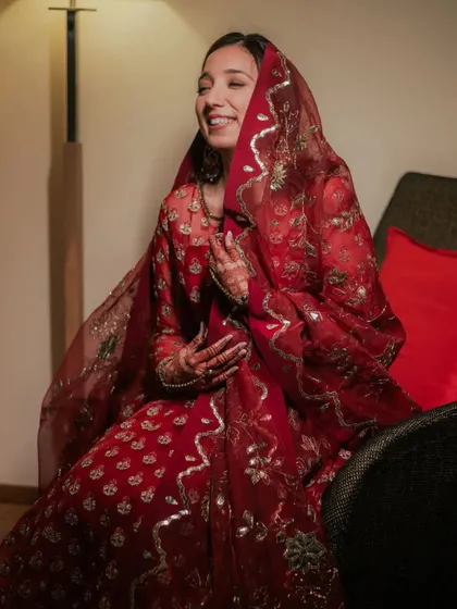 Another angle of this happy bride. The soft lighting highlights the dewy finish of her makeup and the rich color of her outfit.