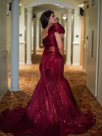 A beautiful back and side profile of the red sculpted gown, highlighting its unique texture and the way it drapes into a stunning train.