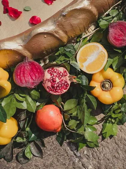 A close-up of the rich textures and colors used in the decor, featuring pomegranates, figs, and bell peppers nestled in fresh greenery.