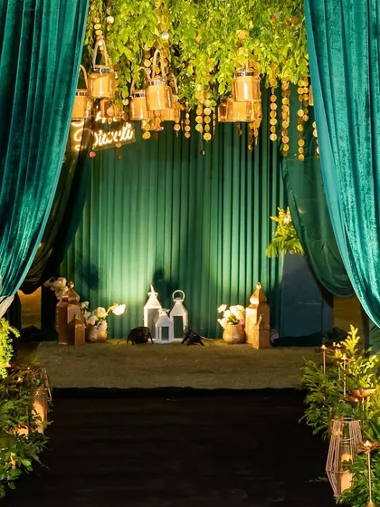 The entrance to the party area was framed with lush emerald velvet curtains, revealing a beautifully lit space with hanging lanterns and greenery, creating a grand sense of arrival.