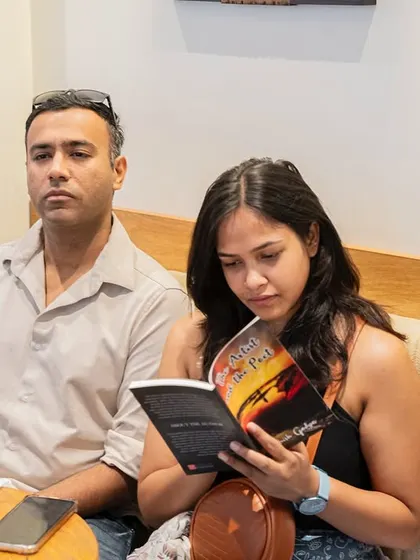 A reader engrossed in her newly acquired copy of "The Artist and the Poet" during the event itself.