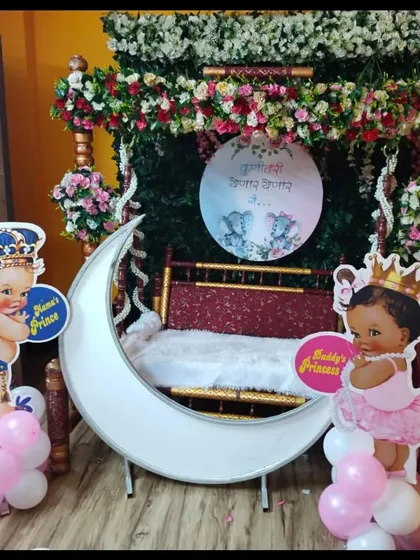 A home baby shower setup with a traditional swing, a lighted moon prop, and cute 'Mama's Prince' and 'Daddy's Princess' cutouts.