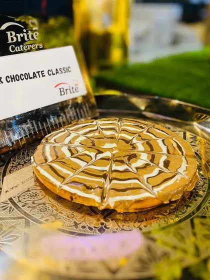 A close-up of a Milk Chocolate Classic waffle, drizzled with a spider-web pattern of white and dark chocolate.