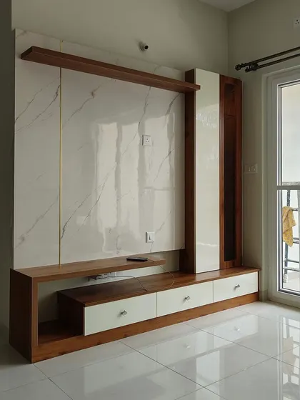 A completed TV unit featuring a white marble back panel with gold-colored inlays and a combination of wood and white laminate finishes, creating a bright and luxurious feel.