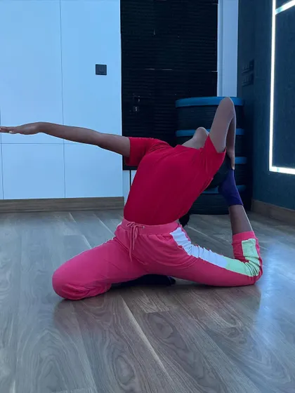 A student performs a deep one-legged king pigeon pose, a testament to the advanced flexibility training I offer.