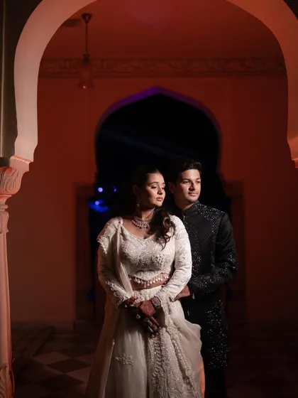 A beautifully composed portrait of the couple framed by an archway. The lighting and their pose create a regal and timeless image from their Sangeet night.