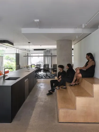 Our new space, Studio 2.0, is designed to foster collaboration, socialization, and focus. This area, with its long kitchen island and tiered wooden seating, serves as the social heart of our studio, a place for informal conversations and shared meals.