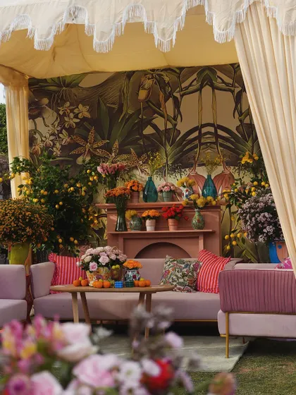 A full view of the canopied seating, showing the comfortable sofas, colorful cushions, and the lush, tropical-inspired mural.