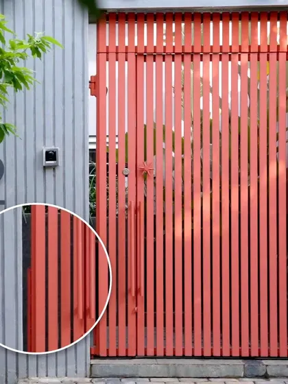 We believe in using color thoughtfully. The bright red of the main gate creates a bold and welcoming entrance, offering a playful contrast to the cool grey tones of the compound wall's vertical fins.