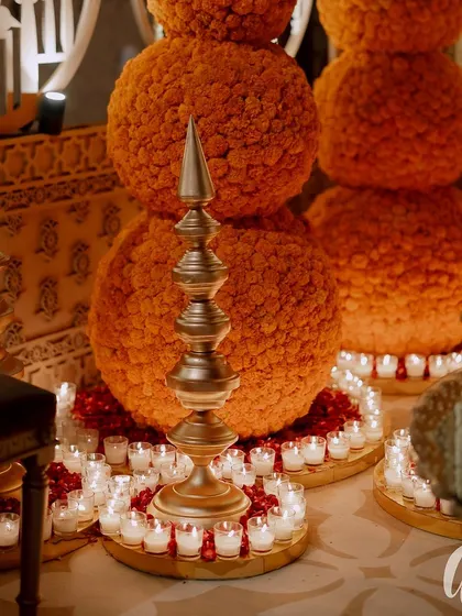 We used traditional elements like marigold spheres and brass temple-style spires, surrounded by a ring of candles, to create these stunning and culturally rich floor decorations.