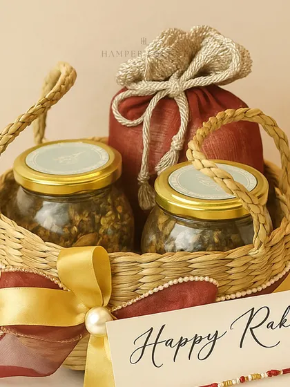 A close-up of the Rakhi jute basket hamper, showing the texture of the basket, the rich colors of the gift pouches, and the elegant "Happy Rakhi" card.
