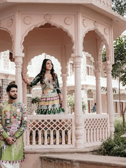 The couple poses in a beautiful gazebo at a palace, their quirky and colorful Haldi outfits making a bold style statement.