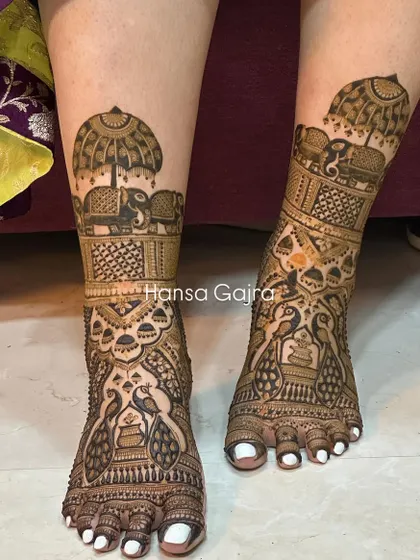 A grand leg design featuring peacocks in a jharokha (window) and royal elephants under an umbrella. This is for the bride who wants her mehendi to be a true work of art.
