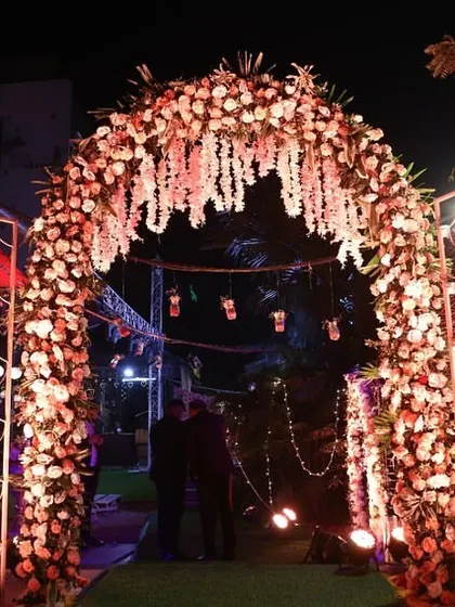 An elegant floral archway for an anniversary party at night, with hanging floral strings and soft lighting creating a romantic entrance.