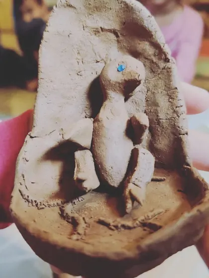 A child holds a clay model of a chick embryo, created as part of their presentation to the class. Making things with their hands helps children process and understand complex biological information.
