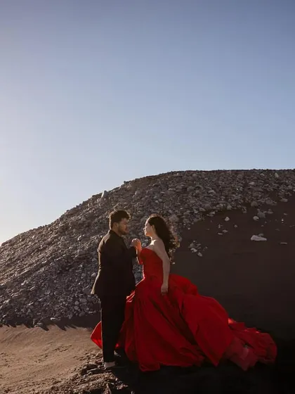 A romantic shot of the couple in Iceland. His textured black blazer and her bold red gown are a perfect example of creating a cinematic, high-fashion pre-wedding look.