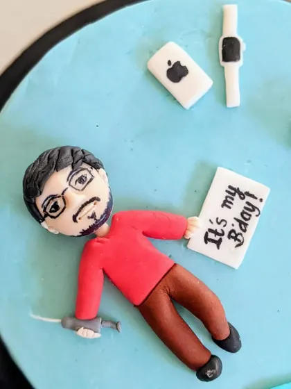 This personalized fondant topper shows a man with his favorite things: his phone, watch, and a sign celebrating his birthday. It's a fun way to customize a cake for a friend or loved one.