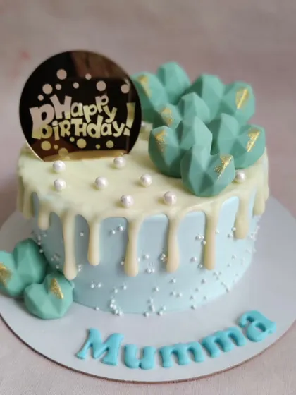 A sweet and simple light blue cake for "Mummy," with a white chocolate drip and pretty teal-colored chocolate hearts.